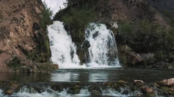 Närbild av ett litet vattenfall i en djup skog. Vackra små turist vattenfall. En liten sjö som faller ett vattenfall — Stockvideo