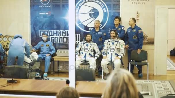 BAIKONUR, KAZAKHSTAN - JULE 28: Tiga kosmonot hidup pergi ke roket, mengucapkan selamat tinggal kepada kerumunan orang, gelombang tangan mereka. Mengenakan pakaian luar angkasa. Peluncuran roket ruang angkasa Soyuz FG MS-05 . — Stok Video