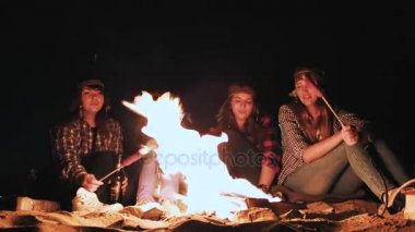 birkaç kız gece ve yavru sosis ateş tarafından otur. Tartışmak ve konuşma yol. Bir kampanya üzerinde gelmiş