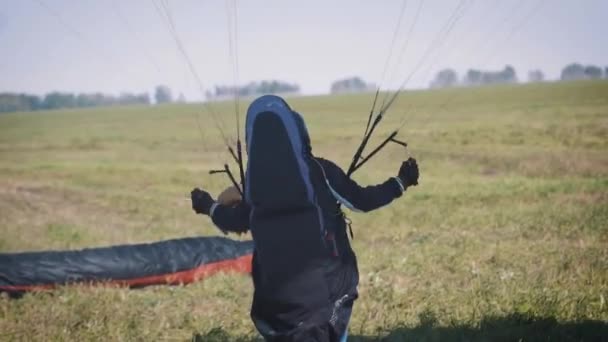 男はをパラグライダーで飛行するには、準備中です。晴れた日にパラグライダーで飛ぶ前に人。男パラグライダー前に極端なスポーツ、パラグライダーのイベント — ストック動画