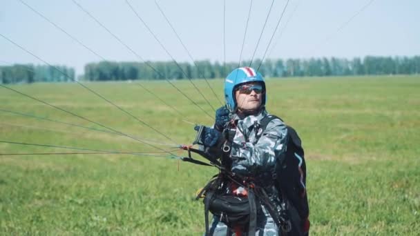 Человек готовится к полёту на параплане. Человек перед полетом на параплане в солнечный день. Before Man Paragliding an Extreme Sports Event On a Paraglider — стоковое видео