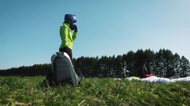 Rapariga parapente. Parapente está pronto para decolar sobre uma colina verde . — Vídeo de Stock