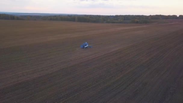 Colpo di drone aereo di una mietitrice che lavora in un campo al tramonto. — Video Stock