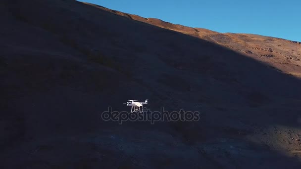 空中ショットで、キャニオンの飛行ドローン。白い大きな quadrocopter、ドローン、山脈の峰の間で飛ぶ。スピンの飛行。ビデオ カメラの本質を削除します — ストック動画