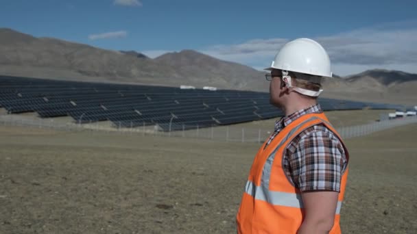 Ingenieur mit Helm und Weste arbeitet an einem Projekt von Solarzellen in der Wüste. — Stockvideo