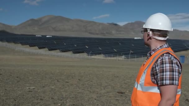 Ingenieur mit Helm und Weste arbeitet an einem Projekt von Solarzellen in der Wüste. — Stockvideo