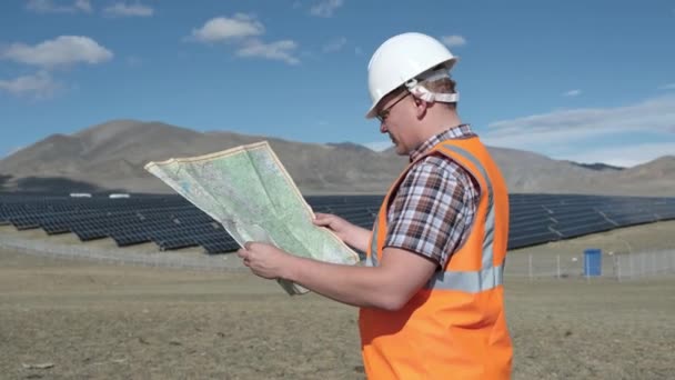 Μηχανικός σε ένα κράνος και γιλέκο εργασίας σε ένα έργο των ηλιακών συλλεκτών στην έρημο. — Αρχείο Βίντεο