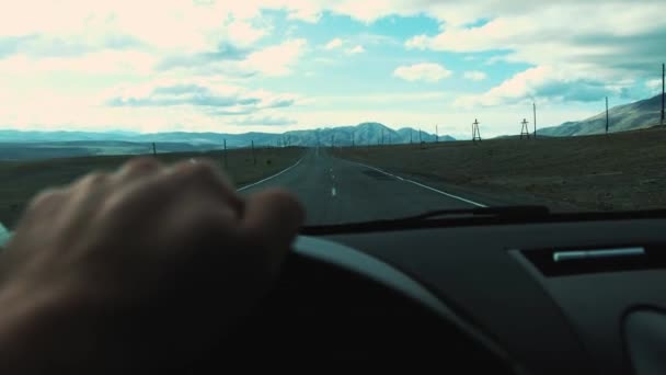 Un hombre conduciendo su auto. Conducir coche en vacaciones, la naturaleza. Hombre Mano en el volante de cerca. Va por la carretera. Se pueden ver las montañas por delante. Viajar en coche . — Vídeo de stock