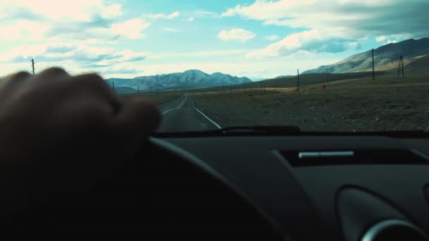 Man driving his car. Driving car at holiday, nature. Male Hand on steering wheel closeup. Goes on the highway. You can see the mountains ahead. Travelling by car. — Stock Video