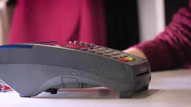 Uma menina faz uma compra com um banco ou cartão de crédito usando um chip eletrônico no cartão. Insira um cartão no terminal de um pagamento sem numerário . — Vídeo de Stock