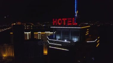 Anteni: Gece şehirde modern bir binanın çatı Neon kırmızı yazıt oteli. Rating arabalar yola gelecek. Bir gökdelenin çatı üzerinde kelime otel