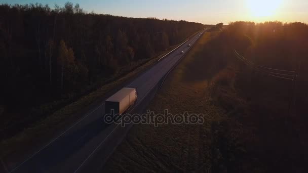 Légi: az autót a konténer lovagolni az út a naplemente. Kamion az autópályán túrák. — Stock videók
