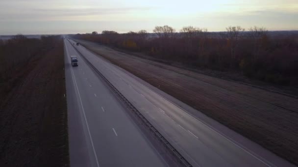 Anteni: güneşe doğru sürüş dağıtım kamyonları. gün batımını giden yolda konteyner ile araba sürmek. Otoyol kamyon sürmek. — Stok video