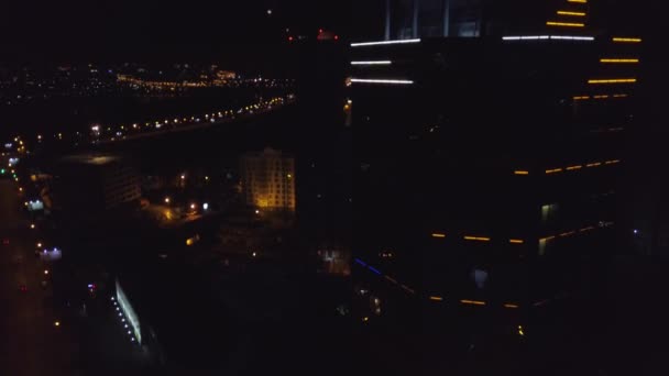 空中: 霓虹灯红色题字旅馆在一个现代大厦的屋顶在夜城市。道路上的交通车辆是下一个。摩天大楼顶上的那个词酒店 — 图库视频影像