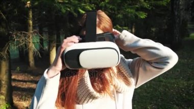 Kız parkta veya ormanın içinde sanal gerçeklik gözlük kullanır. 360 derece oyun oynuyor.