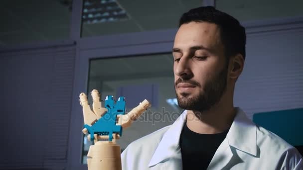 El ingeniero científico masculino experimenta una prótesis biónica de un brazo mecánico. Ve el trabajo de las manos de los robots. Controla el mecanismo por el poder del pensamiento . — Vídeos de Stock