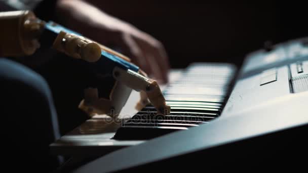 Mann Musiker Pianist mit einer prothetischen Hand beim Klavierspielen. Er spielt mit zwei Händen, einer Roboterhand und einer menschlichen Hand. Roboter schafft Musik und Kunst — Stockvideo