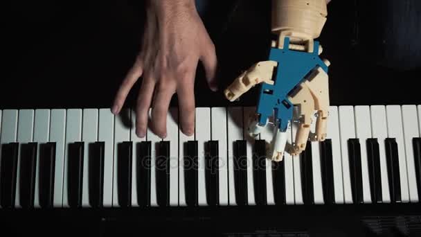 O robô toca um instrumento musical. músico pianista homem com uma mão protética tocando piano. Ele joga com duas mãos, uma mão robô e uma mão humana. Robô cria música e arte — Vídeo de Stock