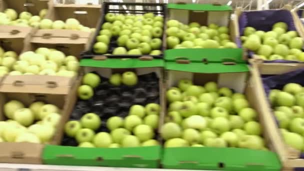 Manzanas verdes frescas maduras a la venta en los estantes del mercado. un montón de manzanas se encuentran en un montón en una caja de cartón en el mostrador — Vídeo de stock