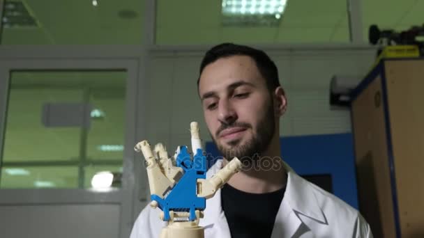 Mannelijke ingenieur wetenschapper ervaringen een bionic prothese van een mechanische arm. Hij horloges het werk van de handen van de robots. Hiermee bepaalt u het mechanisme door de kracht van denken. — Stockvideo