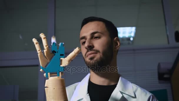 Mannelijke ingenieur wetenschapper ervaringen een bionic prothese van een mechanische arm. Hij horloges het werk van de handen van de robots. Hiermee bepaalt u het mechanisme door de kracht van denken. — Stockvideo