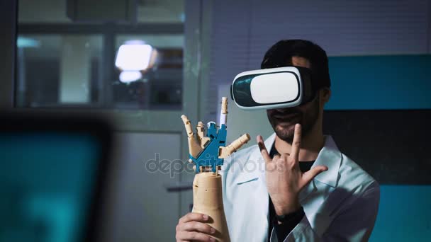 Sistema cibernético hoy. Industria de juegos y seguimiento de movimiento en el ciberespacio. El hombre con gafas innovadoras crea movimiento para el brazo de plástico mecánico. Impresión en impresora 3D. Ciencia ficción y prótesis — Vídeos de Stock