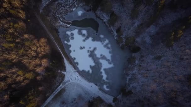 Vol sur un drone au-dessus d'un lac gelé. Des cercles de glace sur l'eau. Lac en hiver dans une forêt ou un parc, parmi les arbres . — Video