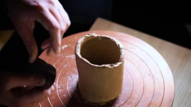 Çömlekçi çarkında çalışan elleri kapatın. Potter çömlekçi çarkında çömlek aletleri ile kil ürünü şekillendirir, üst görünüm, tonlu sinematik, el işi fabrikası otantik