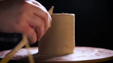 Çömlekçi çarkında çalışan elleri kapatın. Potter çömlekçi çarkında çömlek aletleri ile kil ürünü şekillendirir, üst görünüm, tonlu sinematik, el işi fabrikası otantik