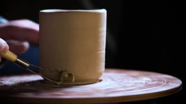 Çömlekçi çarkında çalışan elleri kapatın. Potter çömlekçi çarkında çömlek aletleri ile kil ürünü şekillendirir, üst görünüm, tonlu sinematik, el işi fabrikası otantik