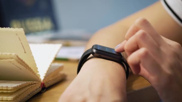 Κάνοντας διάφορες κινήσεις με ένα δάχτυλο στην οθόνη αφής του μια συσκευή φορετά έξυπνο ρολόι. το κορίτσι που κάθεται στο καφενείο, χρησιμοποιεί ένα έξυπνο ρολόι — Αρχείο Βίντεο