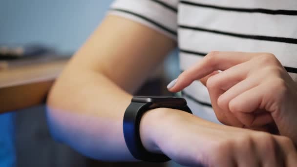 Fazendo vários gestos com um dedo em uma tela sensível ao toque de um dispositivo wearable relógio inteligente. a menina está sentada no café, usa um relógio inteligente — Vídeo de Stock