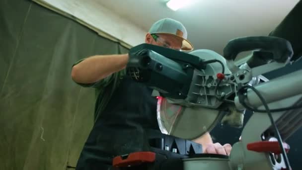 Ein Tischler arbeitet mit einer Spezialmaschine in einem Atelier mit Holz. Der Tischler verwendet eine Kreissägemaschine — Stockvideo