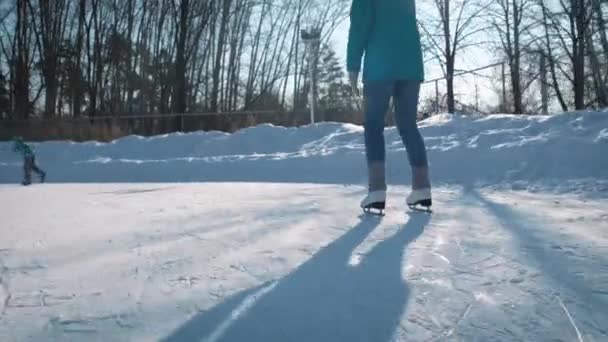 Mujer joven patinando sobre hielo con patines de figuras al aire libre en la nieve — Vídeos de Stock