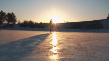 Yakın Up, düşük görüş açısı: Golden sunset büyülü Noel akşamı itibariyle yerel parkta donmuş gölet üzerinde hızlı mutlu bir kadın iceskating. Buz pateni kış aktivitelerini doğada, insanlar eğleniyor