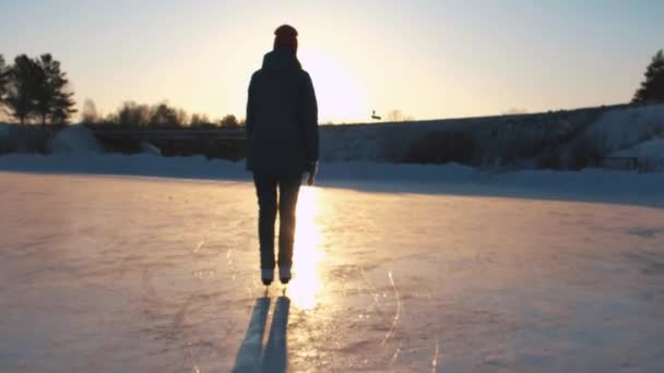 Close Up, lage hoekmening: Gelukkige vrouw schaatsen snel op de bevroren vijver in lokale park bij gouden zonsondergang op magische Kerst avond. Mensen op ijs-of rolschaatsen genieten van Winteractiviteiten in de natuur, plezier — Stockvideo