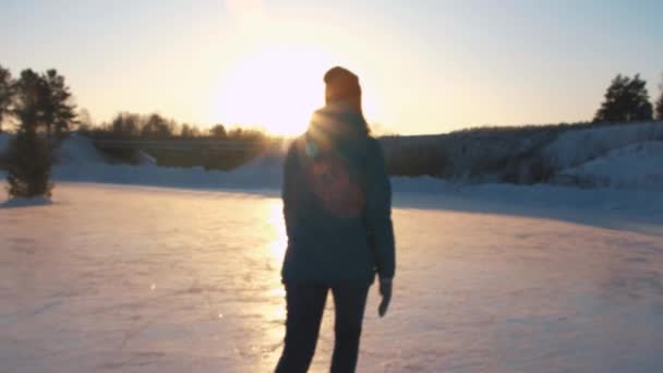 Szoros, alacsony, szög, kilátás: Boldog asszony krikettezik gyorsan a befagyott tó-golden sunset varázslatos Karácsony este a helyi parkban. Emberek a korcsolya élvezi téli lehetőségek jellegét, szórakozás — Stock videók