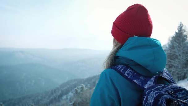 Young girl tourist makes photo on smartphone in winter. Photographs the snow-capped mountains — Stock Video