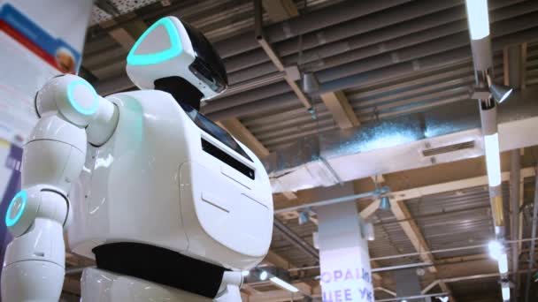 Портрет нового современного белого робота. Робот поворачивает голову, смотрит в камеру. Выставка роботов и высоких робототехнических технологий — стоковое видео