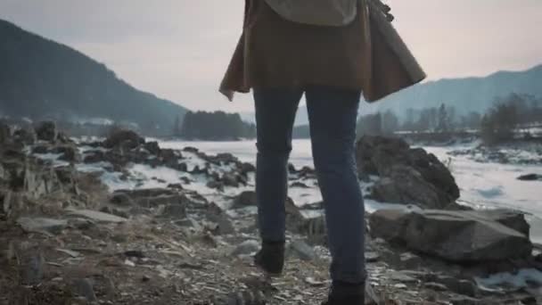 Een jong meisje reist naar een bevroren rivier en verhoogt haar handen omhoog. Geniet van het leven, houdt van reizen. — Stockvideo