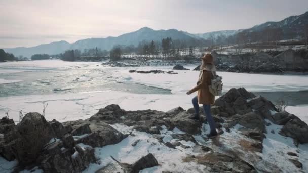Une jeune fille se rend sur une rivière gelée et lève les mains. Profite de la vie, aime voyager . — Video