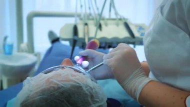 Dişçi ofiste iş başında. Kadın doktor diş ve çene erkek hastanın inceliyor..