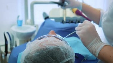 Dişçi ofiste iş başında. Kadın doktor diş ve çene erkek hastanın inceliyor..