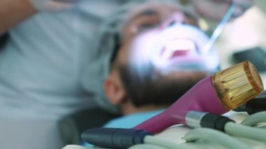 Dişçi ofiste iş başında. Kadın doktor diş ve çene erkek hastanın inceliyor..