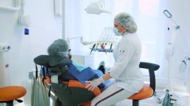 Sağlık ve diş bakımı, diş hekimi ve Doktor, işyerinde kadın erkek bir hasta için söz. Diş tedavisi profesyonel laboratuvar tartışmak. Steadicam atış.