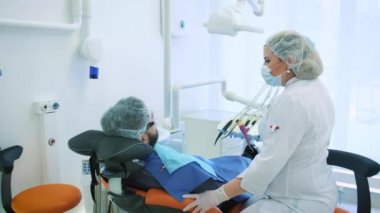 Sağlık ve diş bakımı, diş hekimi ve Doktor, işyerinde kadın erkek bir hasta için söz. Diş tedavisi profesyonel laboratuvar tartışmak. Steadicam atış.