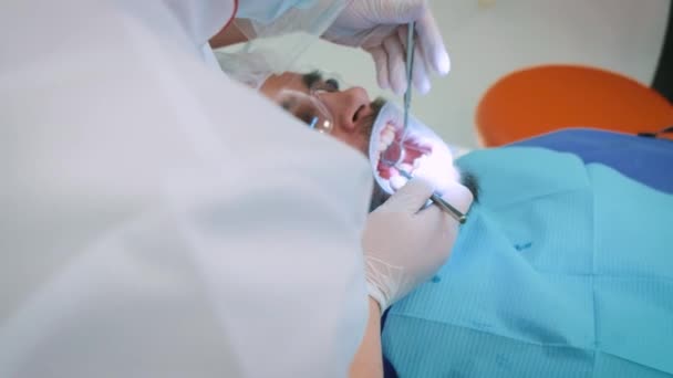 Дантист на работе в офисе. Женщина-врач осматривает зубы и челюсти пациента-мужчины .. — стоковое видео