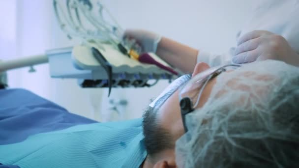 Dentista trabajando en la oficina. Una doctora examina los dientes y las mandíbulas de un paciente masculino .. — Vídeos de Stock