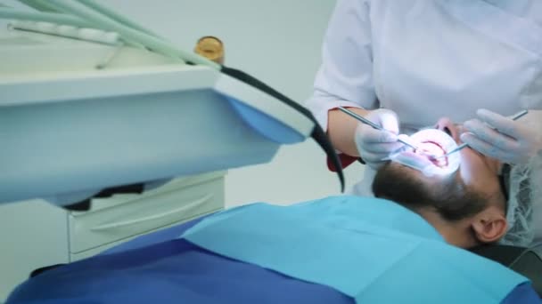 Zahnarzt bei der Arbeit im Büro. Ärztin untersucht Zähne und Kiefer eines männlichen Patienten.. — Stockvideo