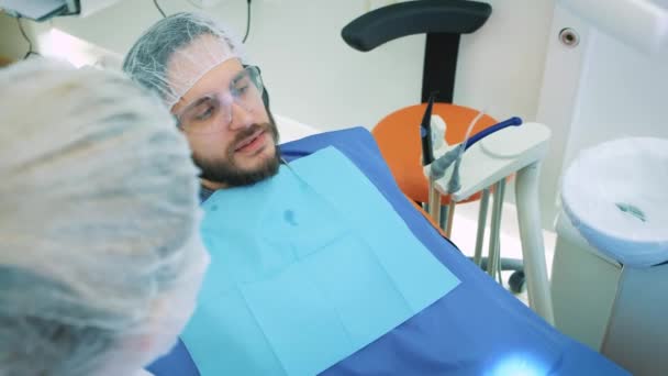 Hälso- och tandvård, kvinna på jobbet som tandläkare och läkare, prata med en manlig patient. Diskutera tandvård i professionell laboratorium. Steadicam skott. — Stockvideo